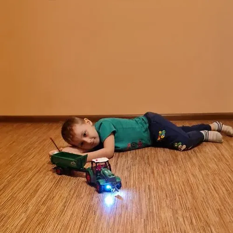 Dítě při hře se zeleným traktorem Kruzzel 24850 s rozsvícenými předními světly