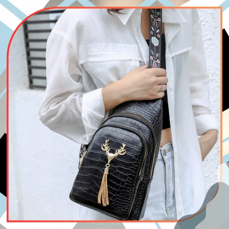 Elegantní dámská crossbody ledvinka ROL115 černá s krokodýlím vzorem nošená přes rameno. Voděodolná ledvinka z eko kůže s nastavitelným popruhem pro každodenní nošení i cestování.